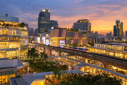 Bright mall atrium in Bangkok with shoppers and bags