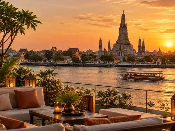 Riverside rooftop at golden hour with a temple spire across the Chao Phraya