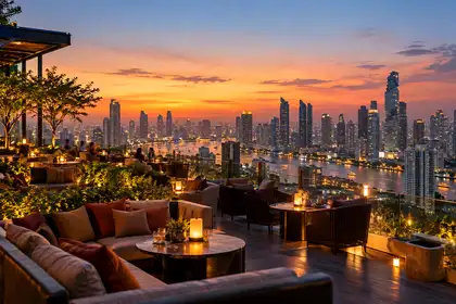 Rooftop bar in Bangkok at dusk with the skyline behind the tables