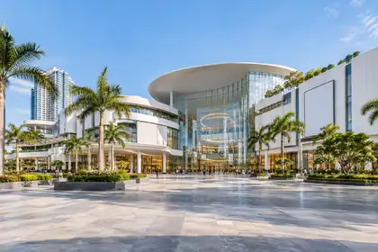 Large modern shopping mall with a glass and white facade and palm trees on a bright morning