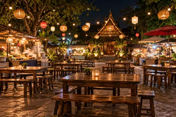 Food court tables under warm lights with plates of Northern Thai street food in Chiang Mai