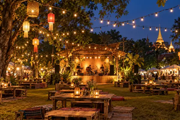 Night market with a small live music stage, string lights and food stalls on a lawn in Chiang Mai