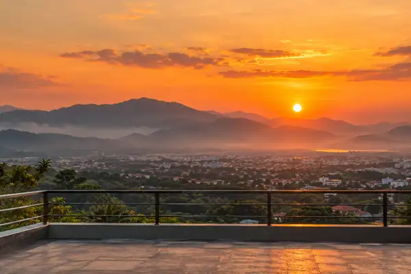 Indy Massage Chiang Mai: orange sunset over the hills near Chiang Mai seen from a rooftop rail