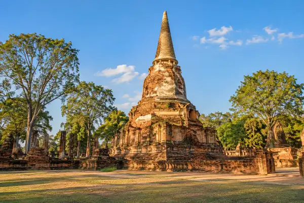 Huge ancient brick chedi in a temple courtyard under a clear blue sky