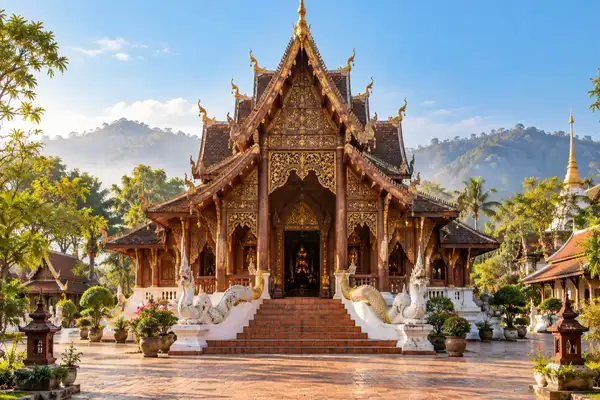 Carved wooden Lanna style temple hall with a layered roof and a calm courtyard