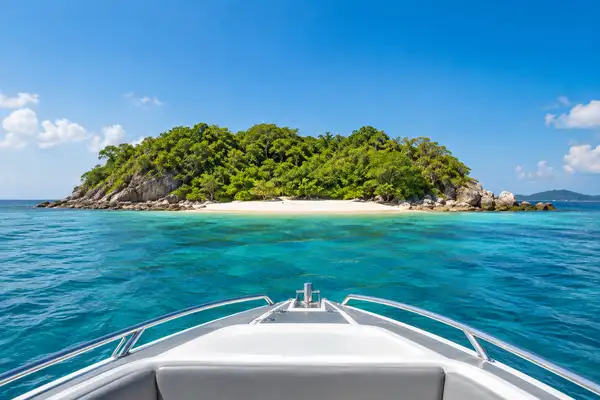 Small green island with a pale beach and clear turquoise water off the coast of Pattaya