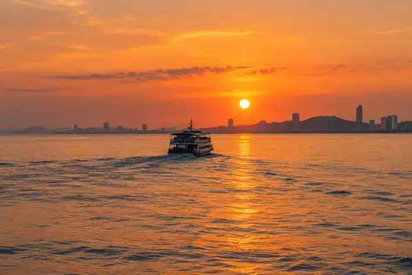 Orange sunset over the calm Gulf of Thailand with a ferry boat heading back toward Pattaya
