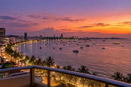 Indy Massage Pattaya: Pattaya nightlife guide hero, the bay at dusk with the lit curve of Beach Road