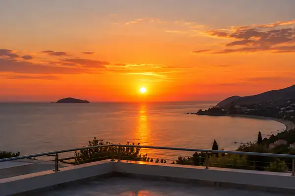 Indy Massage Pattaya: orange sunset over the Pattaya sea with an island silhouette seen from a rooftop rail