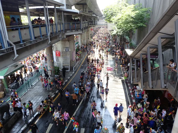 People walking through a busy Bangkok city area during festival season