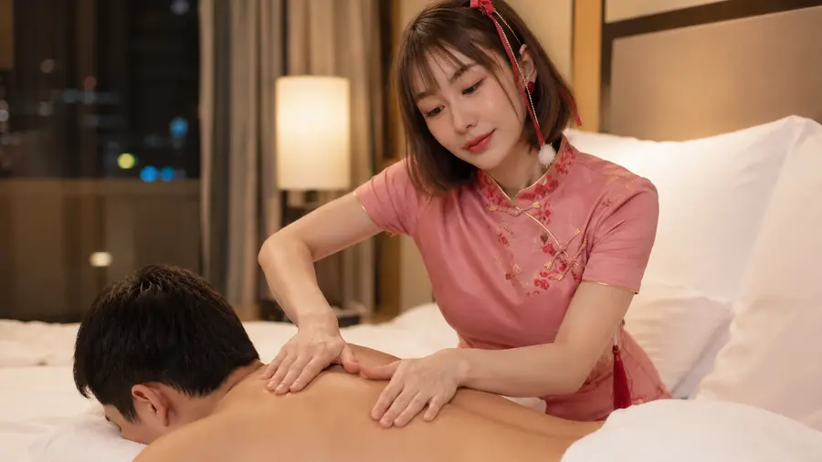 In room massage near Mercure Bangkok Sukhumvit 11, therapist in pink giving a back massage on a bed | Indy Massage Bangkok