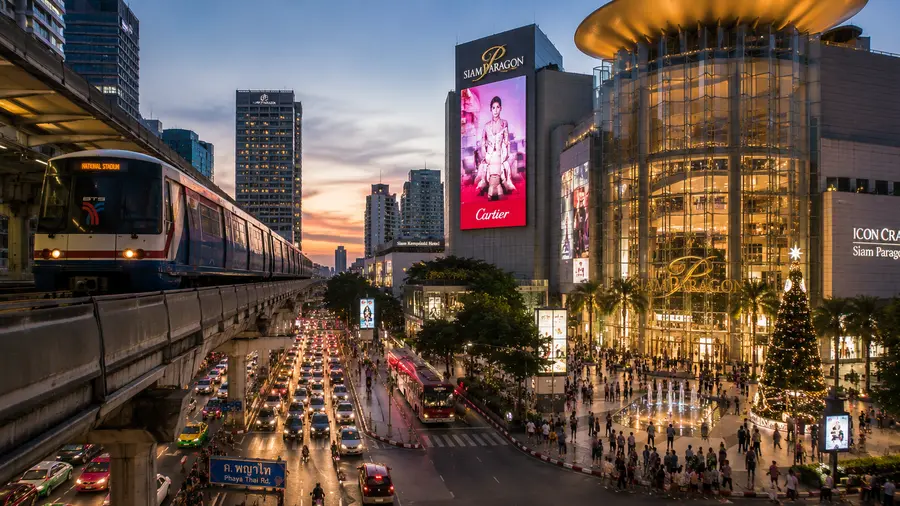 In room massage near Park Origin Phrom Phong, with the BTS Skytrain and a shopping mall at dusk | Indy Massage Bangkok